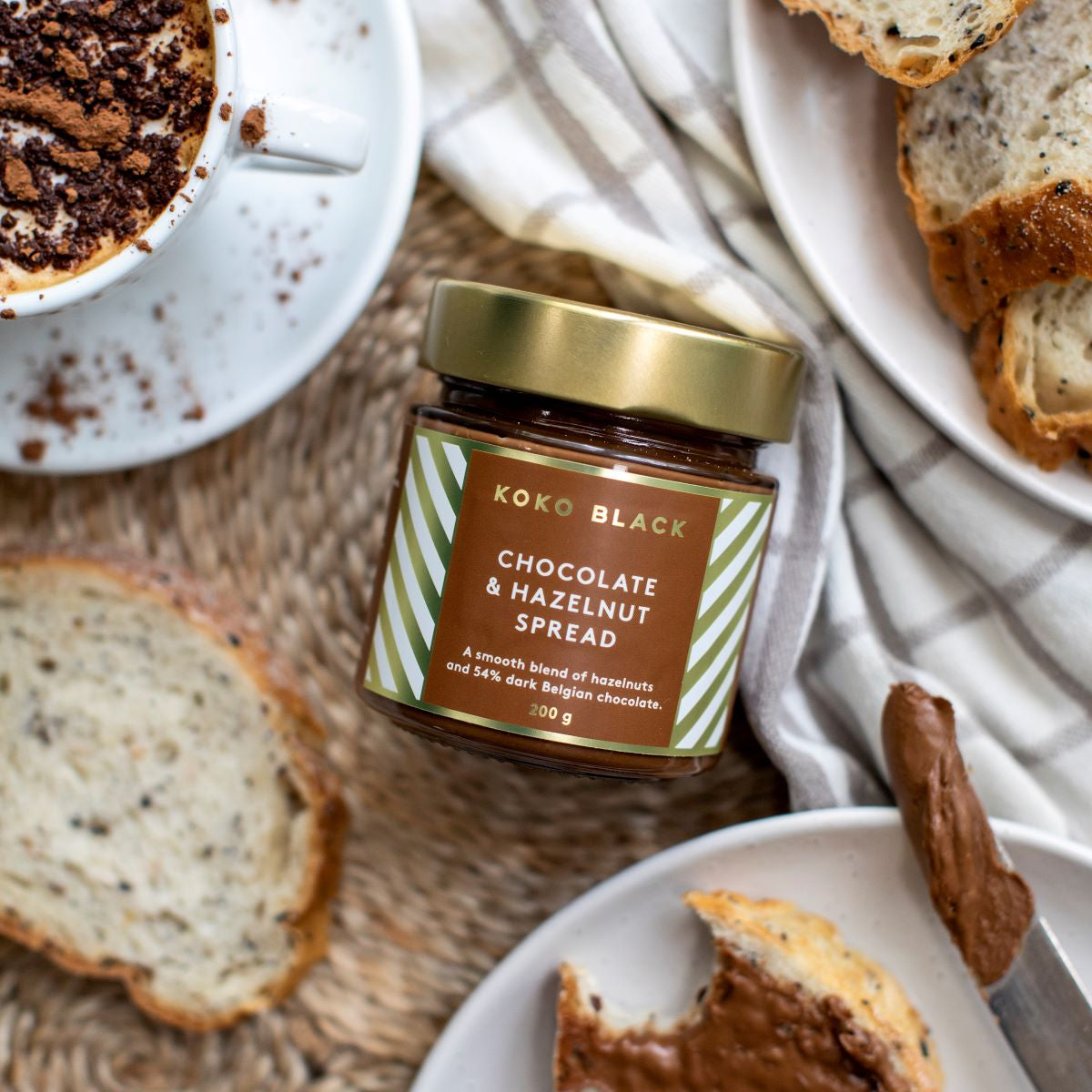 Jar of spread centered around toast, cappucino and butter knife